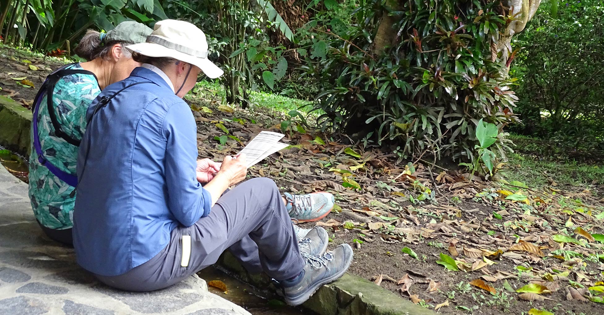 Two people sit outdoors and review a bird checklist together
