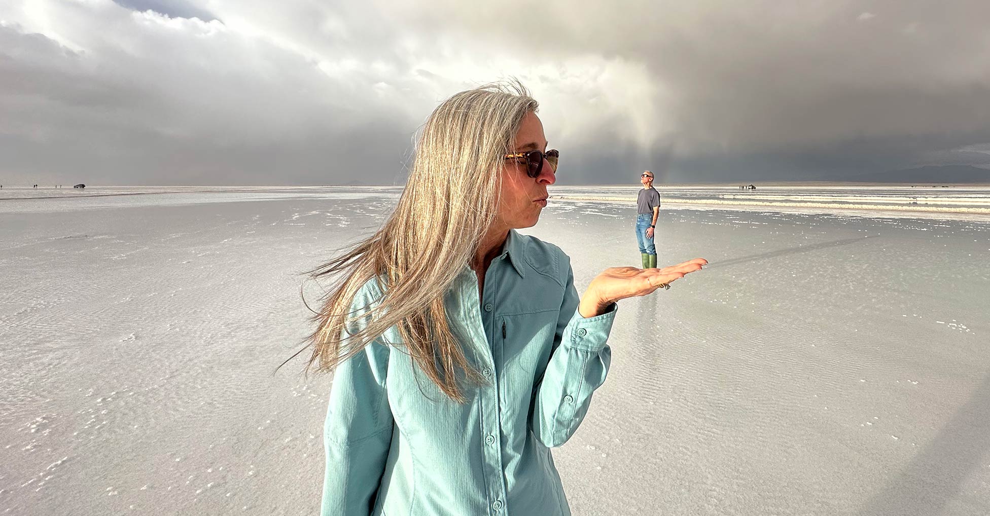 A person in the foreground appears to hold on their open palm a much smaller person standing in the distance, an optical illusion.