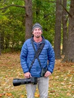 Jon standing with a camera in the forest