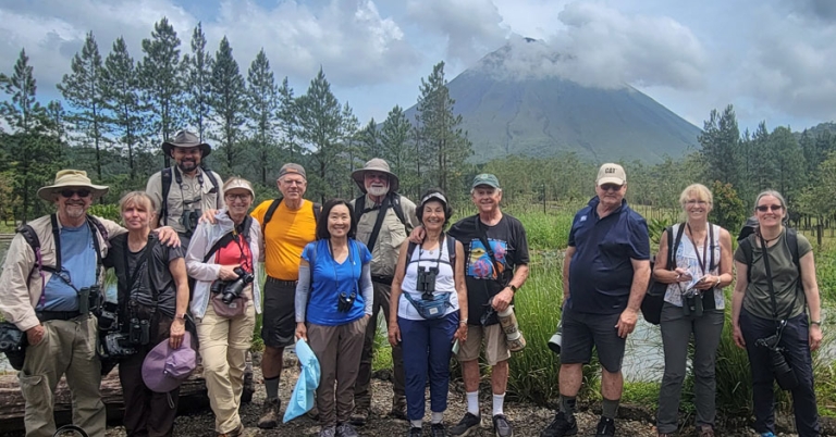 Group of travelers smiling with Arenal Volcano in background