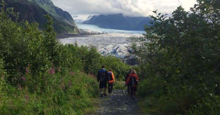 Group hiking down path with glacier in the distance