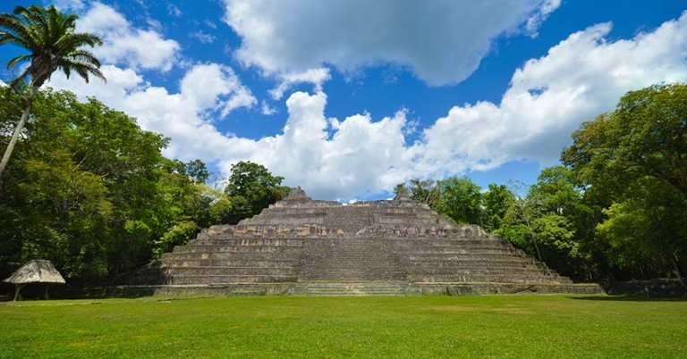 A stone pyramidal structure with a broad central stairway and trees on either side