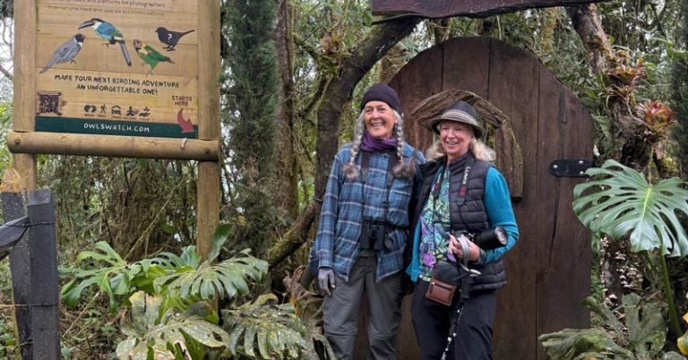 two travelers posing in from of the signs for Owl's Watch