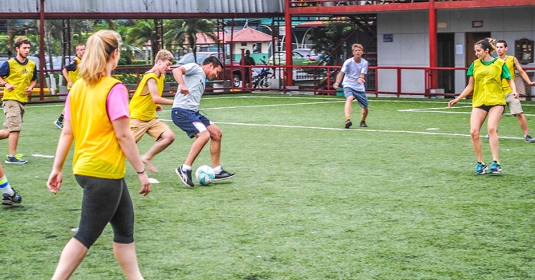 A young man on a soccer field prepares to kick a soccer ball while several other players watch