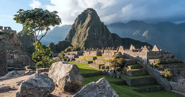 The remains of a series of stone buildings with the Huayna Picchu mountain in the background