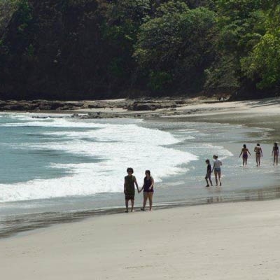 several groups of tourists walk along the beach