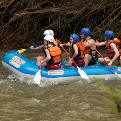 Group of five students and a guide sit in a raft on the river