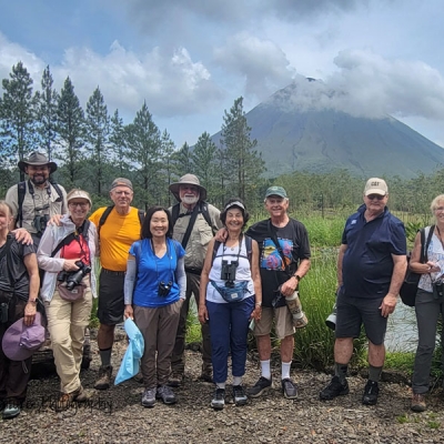Group of travelers smiling with Arenal Volcano in background