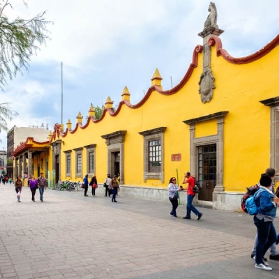 A few groups of tourists strolling in front of a brightly colored building