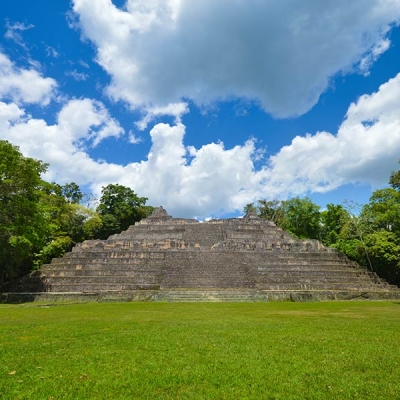 A stone pyramidal structure with a broad central stairway and trees on either side