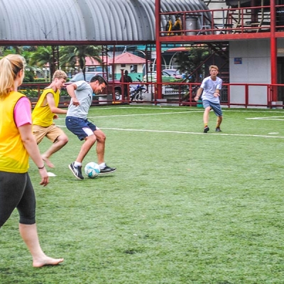 A young man on a soccer field prepares to kick a soccer ball while several other players watch