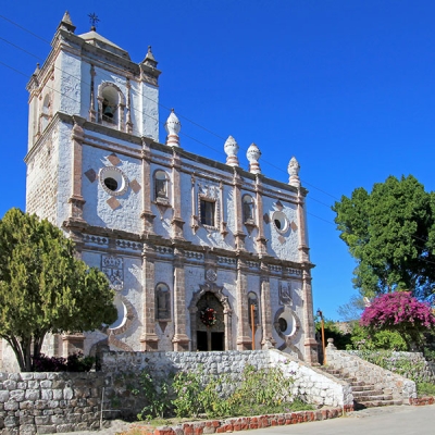 The exterior of a Spanish mission-style church with cut stone construction