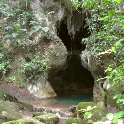 A limestone cave entrance with a pool of water at the base