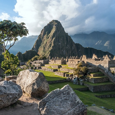 The remains of a series of stone buildings with the Huayna Picchu mountain in the background