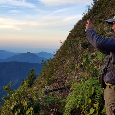 A person takes a picture of a mountainous landscape in early morning light