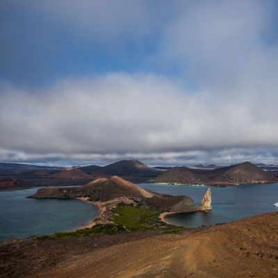 Island landscape with a sharp, rocky geological feature jutting up from the water