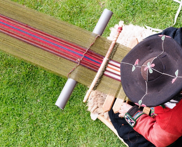 An Indigenous weaver works on a traditional backstrap loom