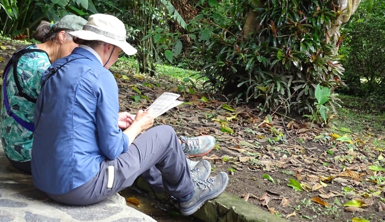 Two people sit outdoors and review a bird checklist together