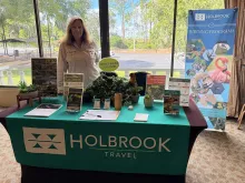 Woman standing behind a conference table decorated with Holbrook-branded signage and handouts