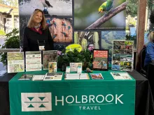 Woman standing behind a conference table decorated with Holbrook-branded signage and handouts