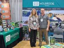 Staff members Debbie Jordan and Kevin Van Dien stand in a conference booth decorated with Holbrook-branded signs and handouts.